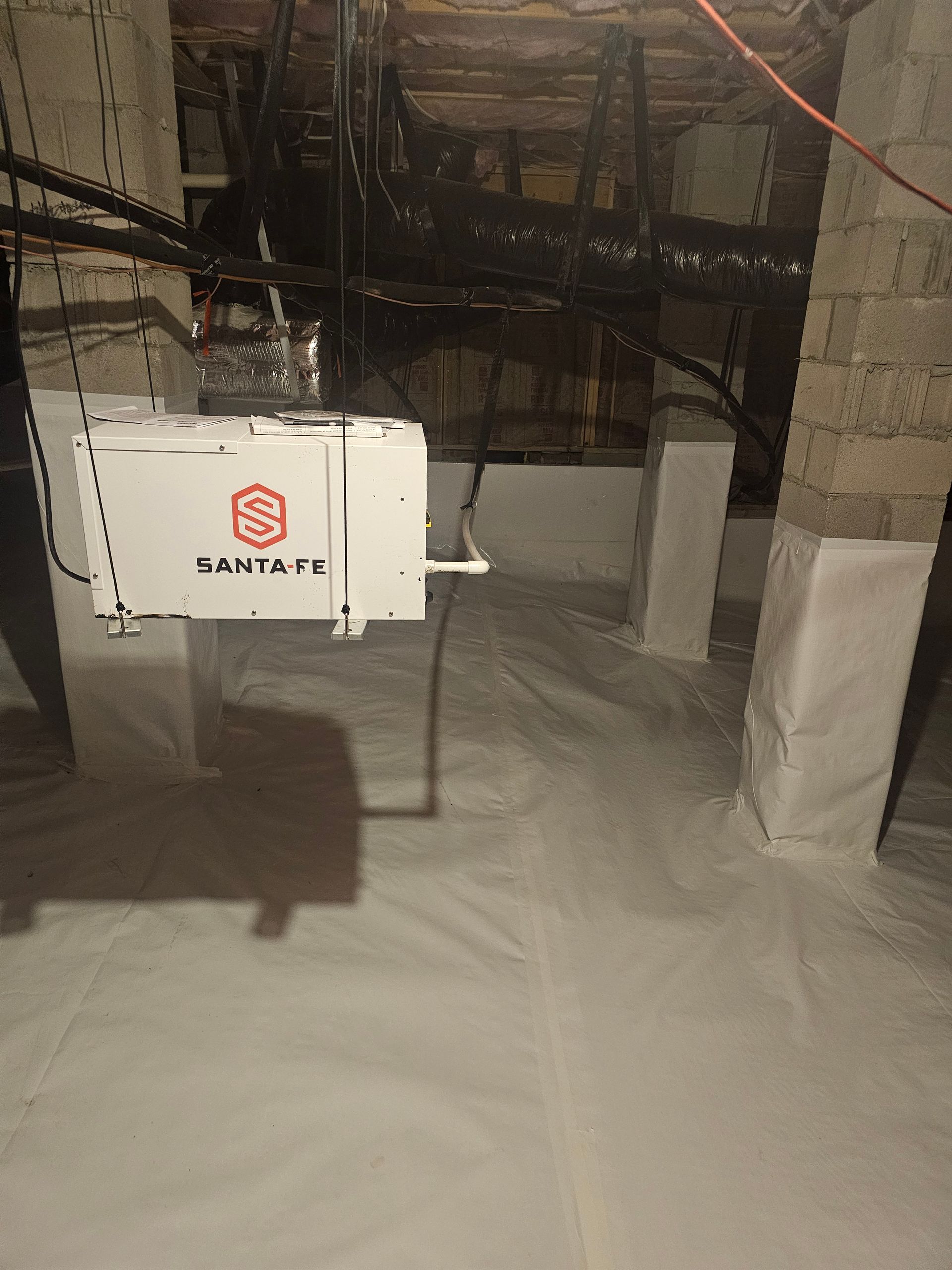 A white box is hanging from the ceiling of a basement.