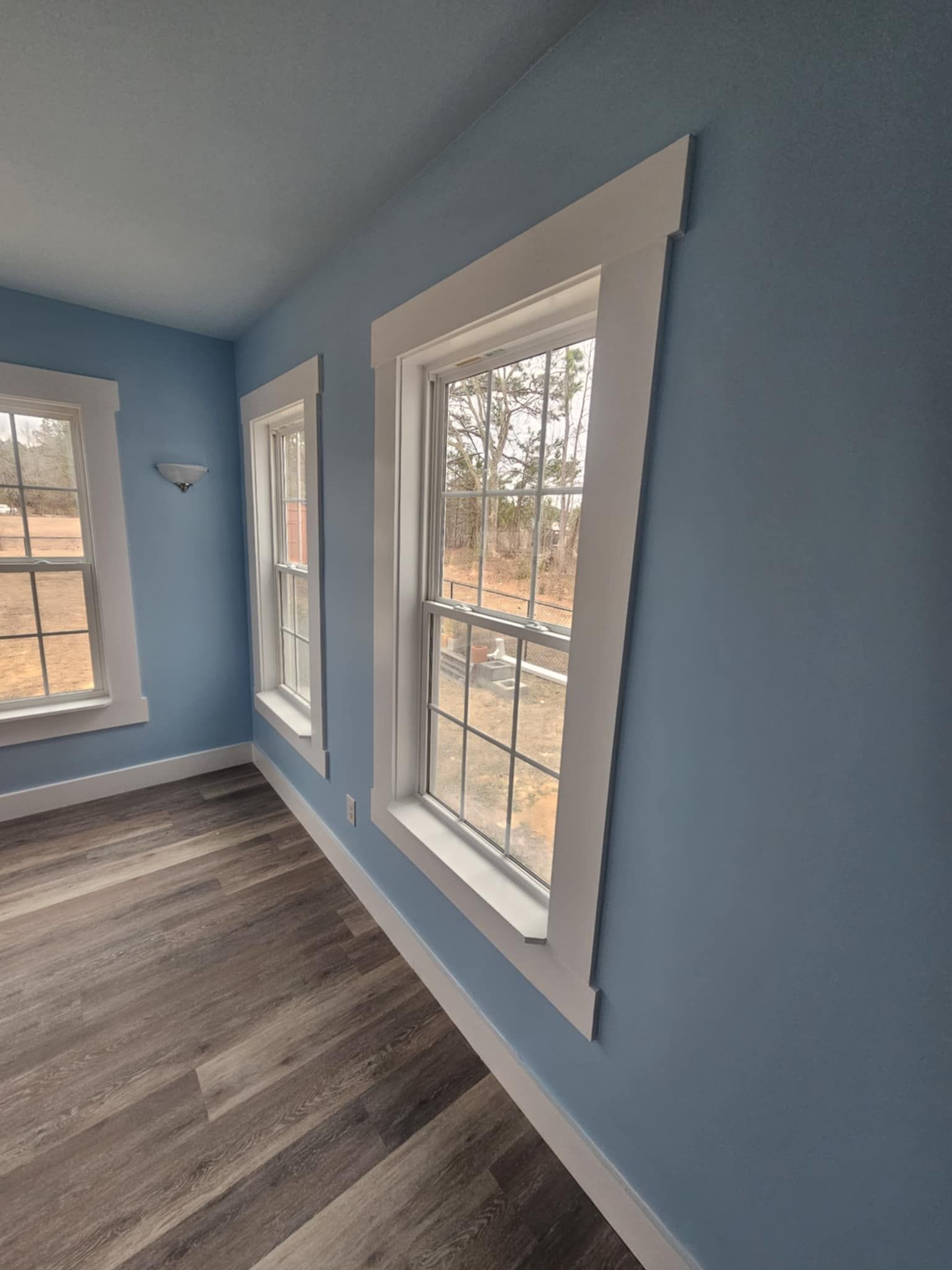 A room with blue walls white trim and three windows.