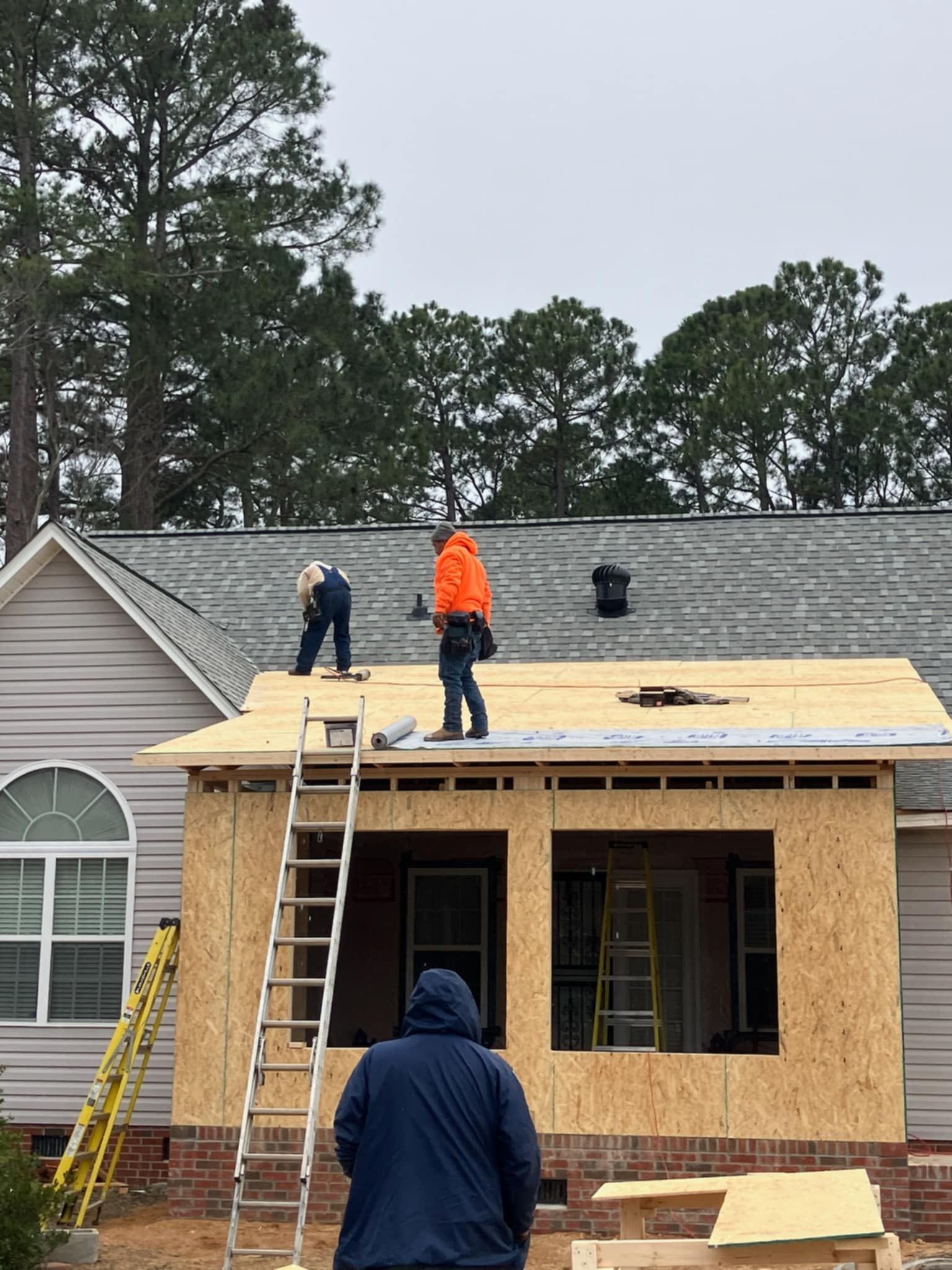 Two men are working on the roof of a house.