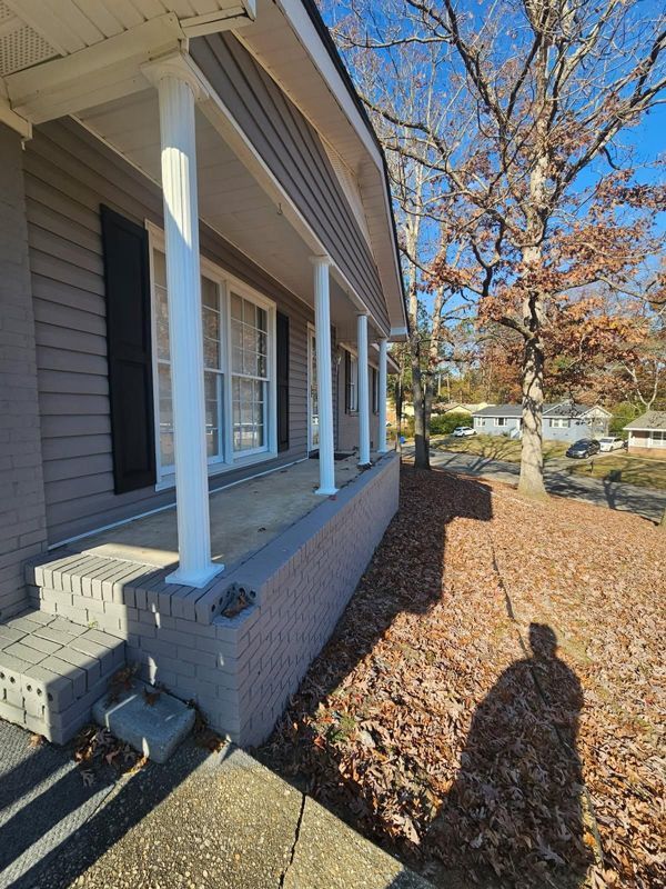 A house with a porch and a tree in the background.