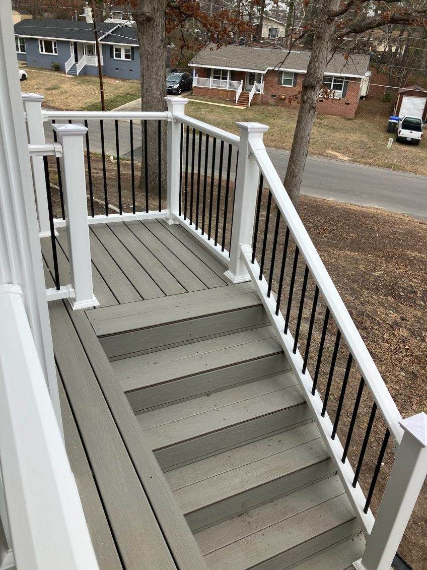 A deck with stairs leading up to it and a white railing.