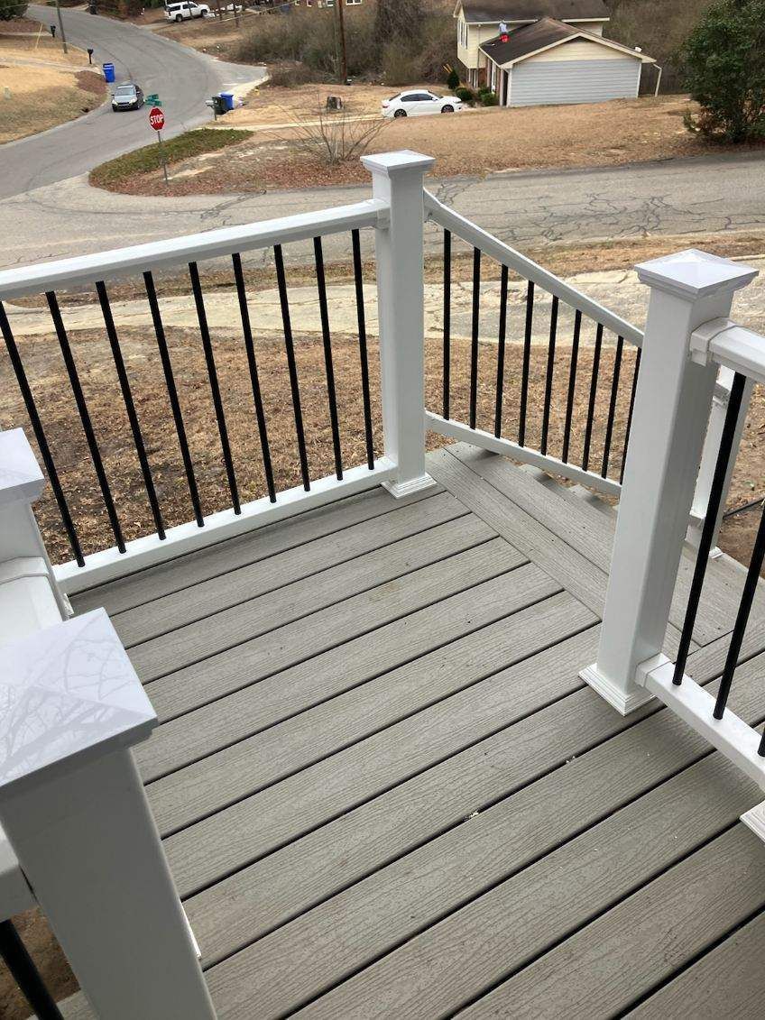A deck with a white railing and stairs leading up to it.