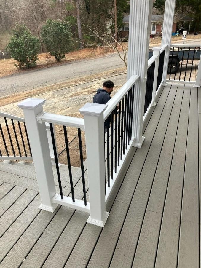 A man is standing on a deck with a white railing.