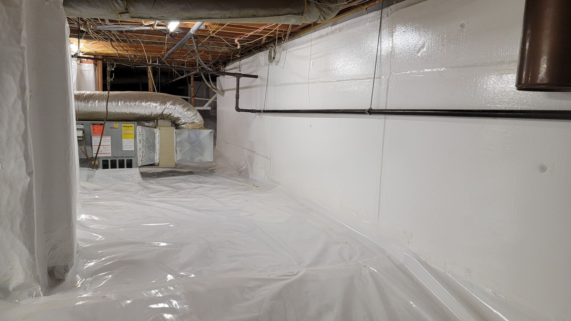 A basement with a lot of plastic on the floor and walls.