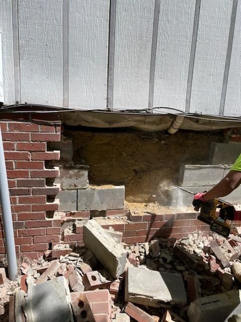 A man is cutting a hole in a brick wall with a saw.