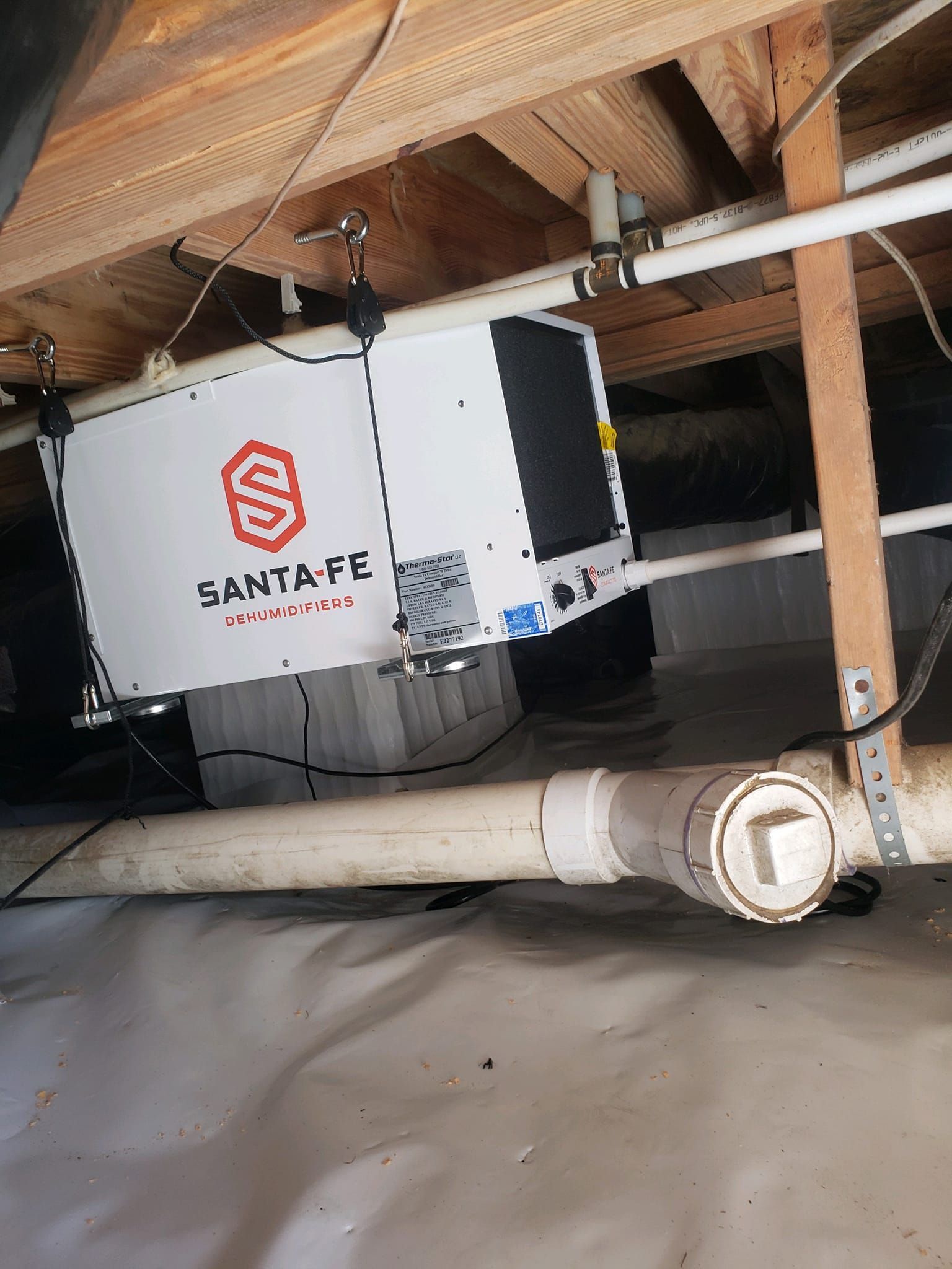 A santa fe air conditioner is hanging from the ceiling of a basement.