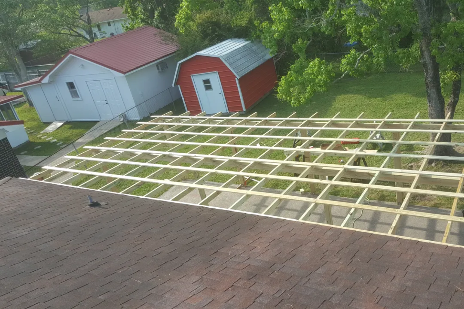 Wooden framework construction on a rooftop, with red and white buildings in the background.