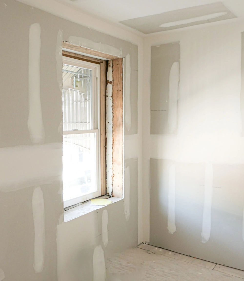 Room under construction with drywall, a window, and visible seams.
