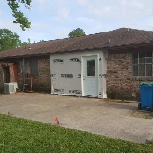 Back of a brick house with a newly constructed white door addition.
