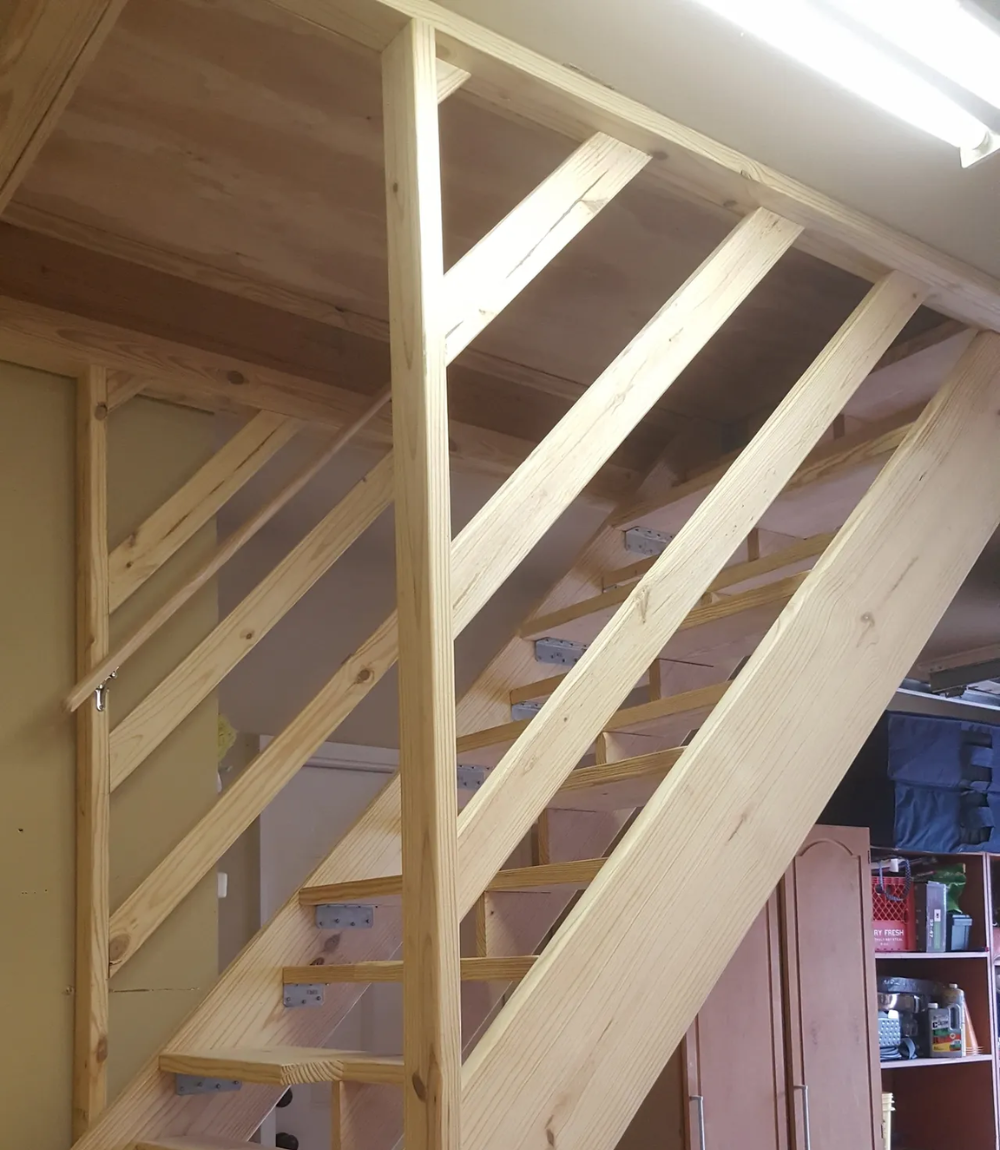 Wooden staircase with diagonal support beams, ascending to an upper level.