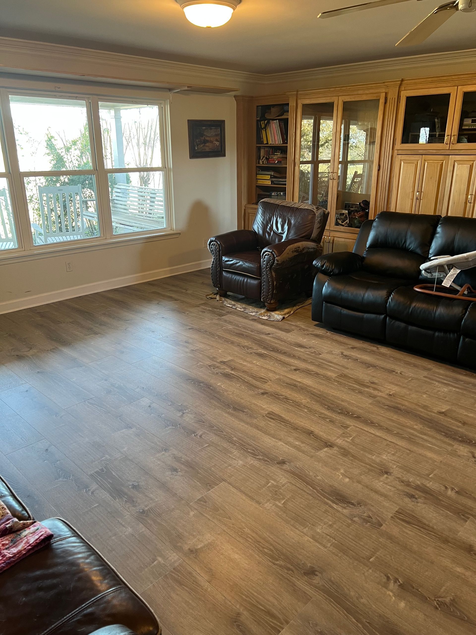 Living room with hardwood floors, two dark leather chairs, and a window.