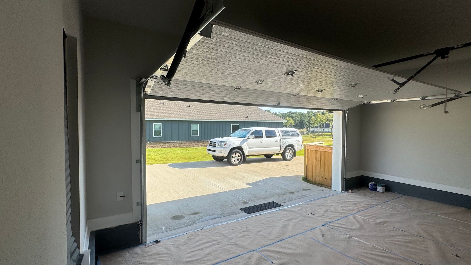Garage interior with a white truck parked outside. The garage door is open.
