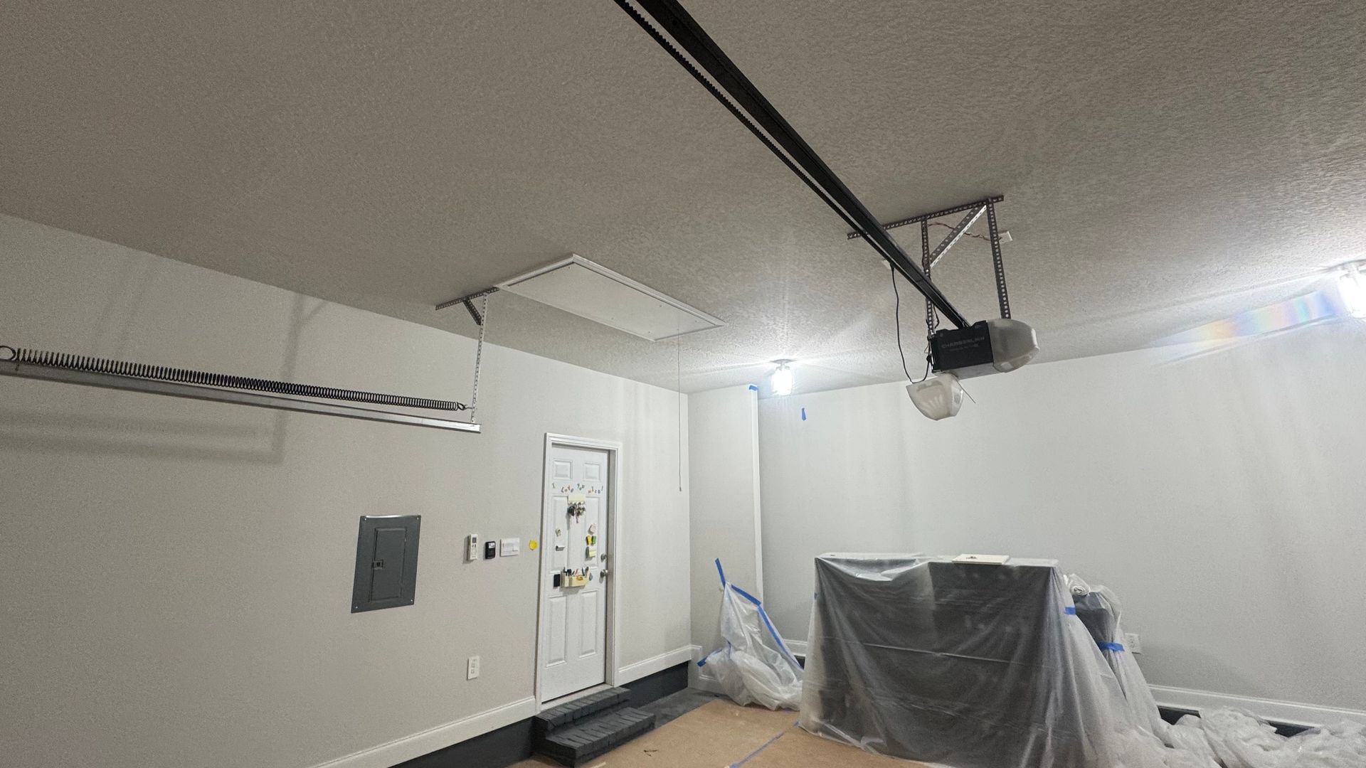Garage interior with a gray ceiling, white walls, and a garage door opener.