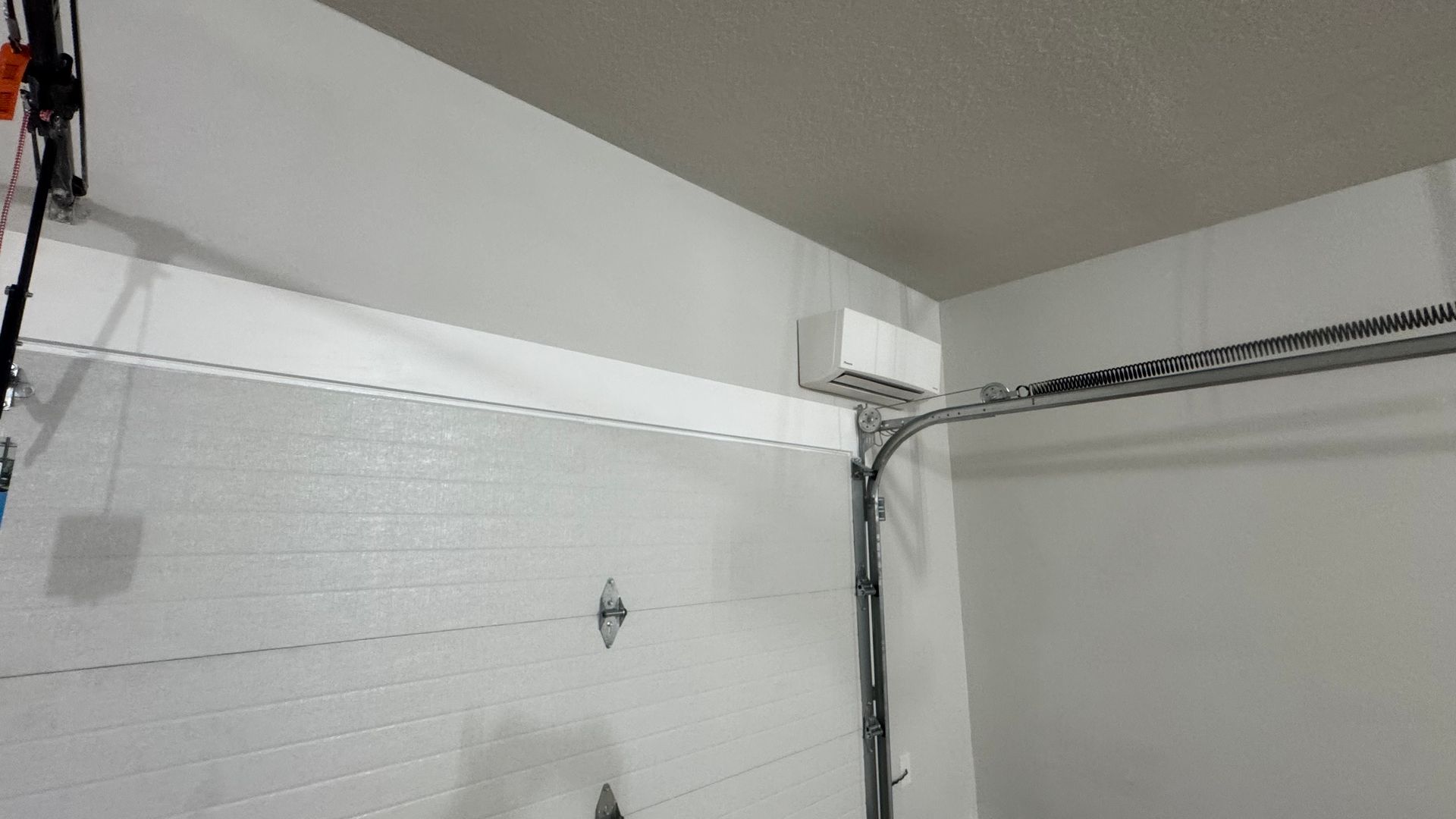 Garage door opener mounted on the ceiling, with chain drive and white door.