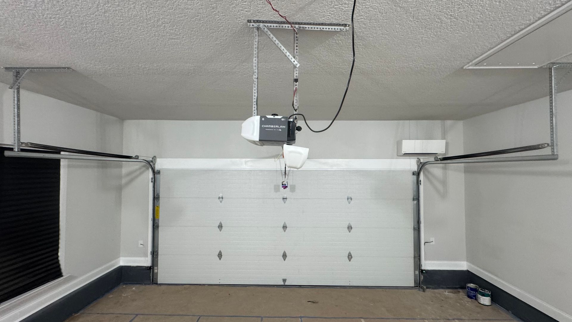 Garage interior with a white garage door, opener, and steel support beams.
