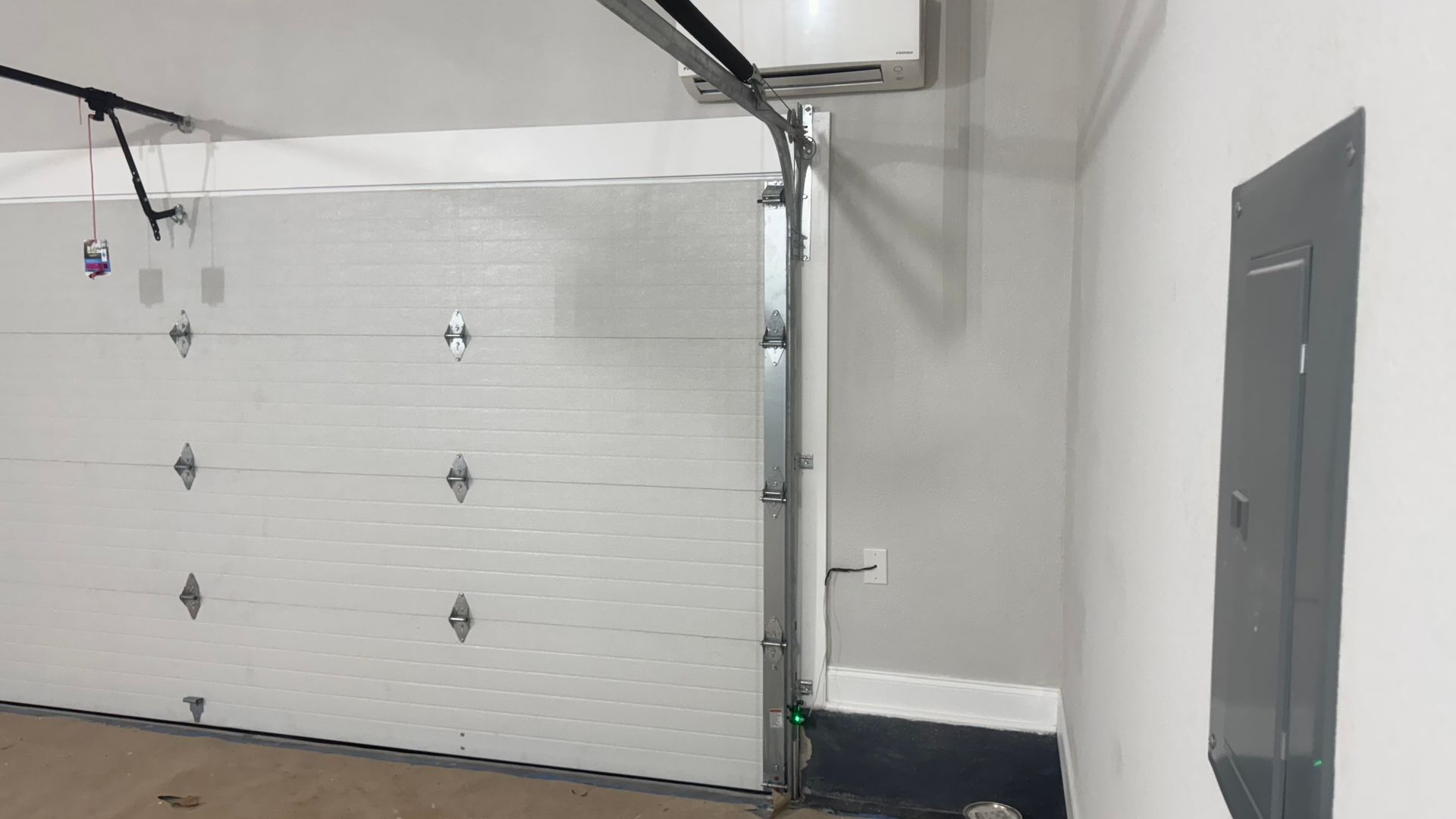 White garage door, partially open, with a gray electrical panel on the right side.