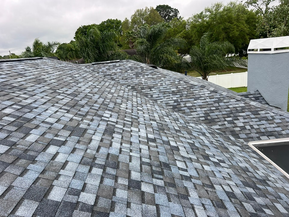 A roof with a lot of shingles on it and trees in the background.