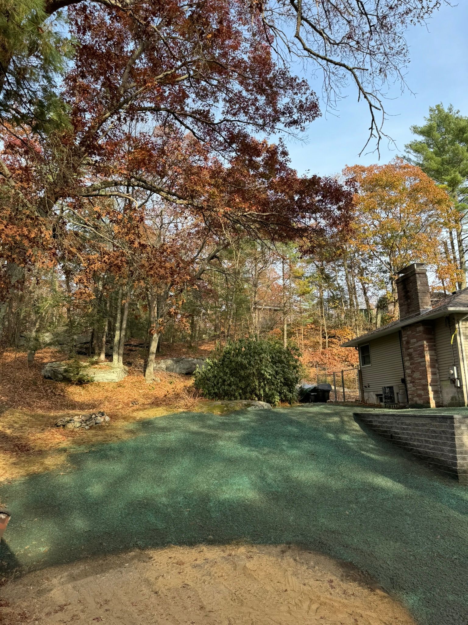 Autumn trees with colorful leaves behind a grassy lawn and a stone building.