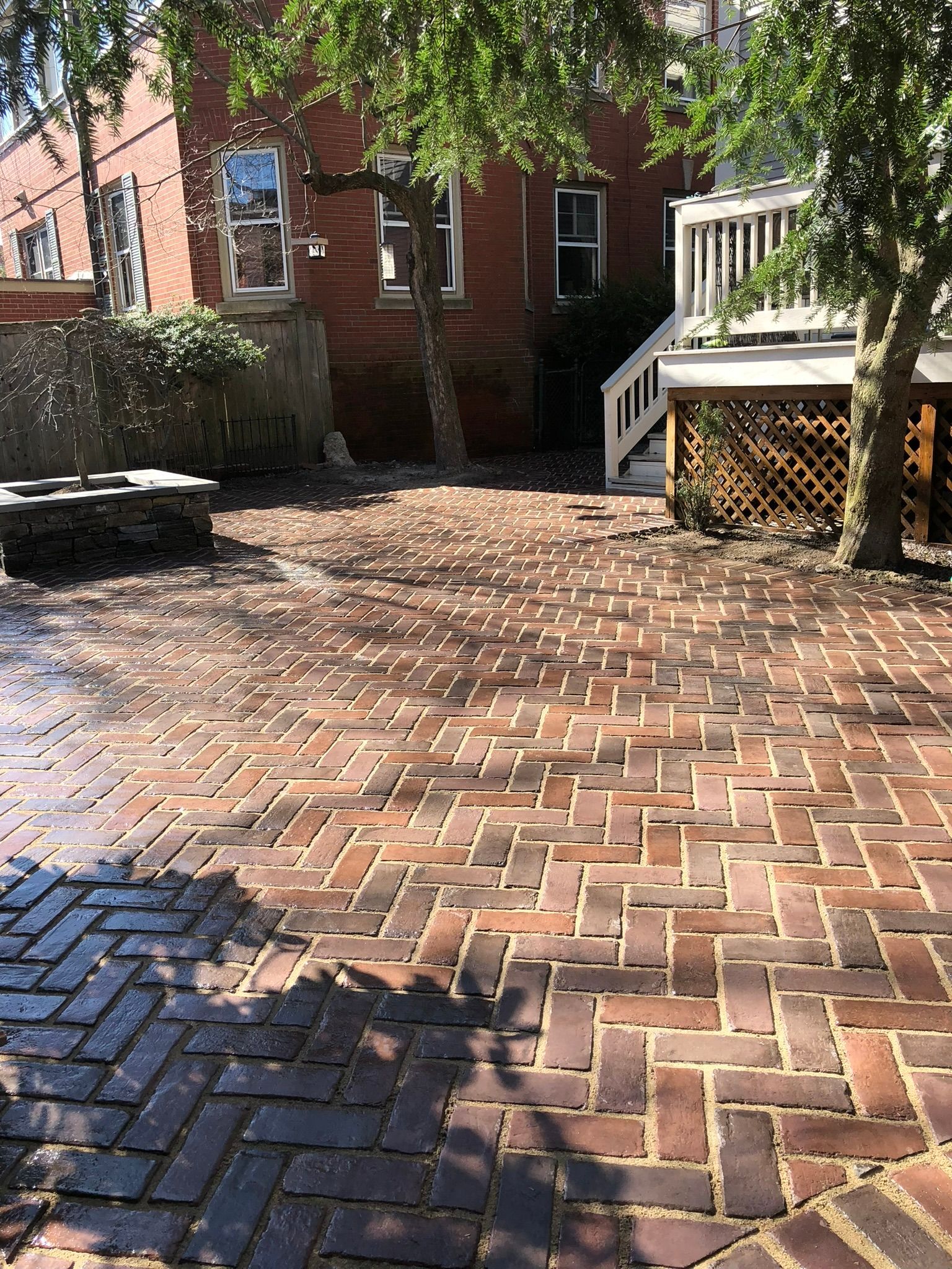 A brick patio with a fire pit in the middle of it in front of a brick building.