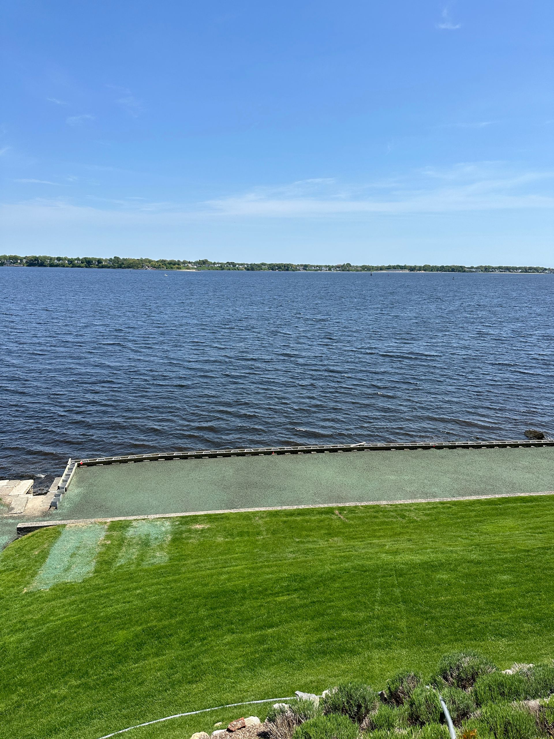 A large body of water is surrounded by a lush green field.
