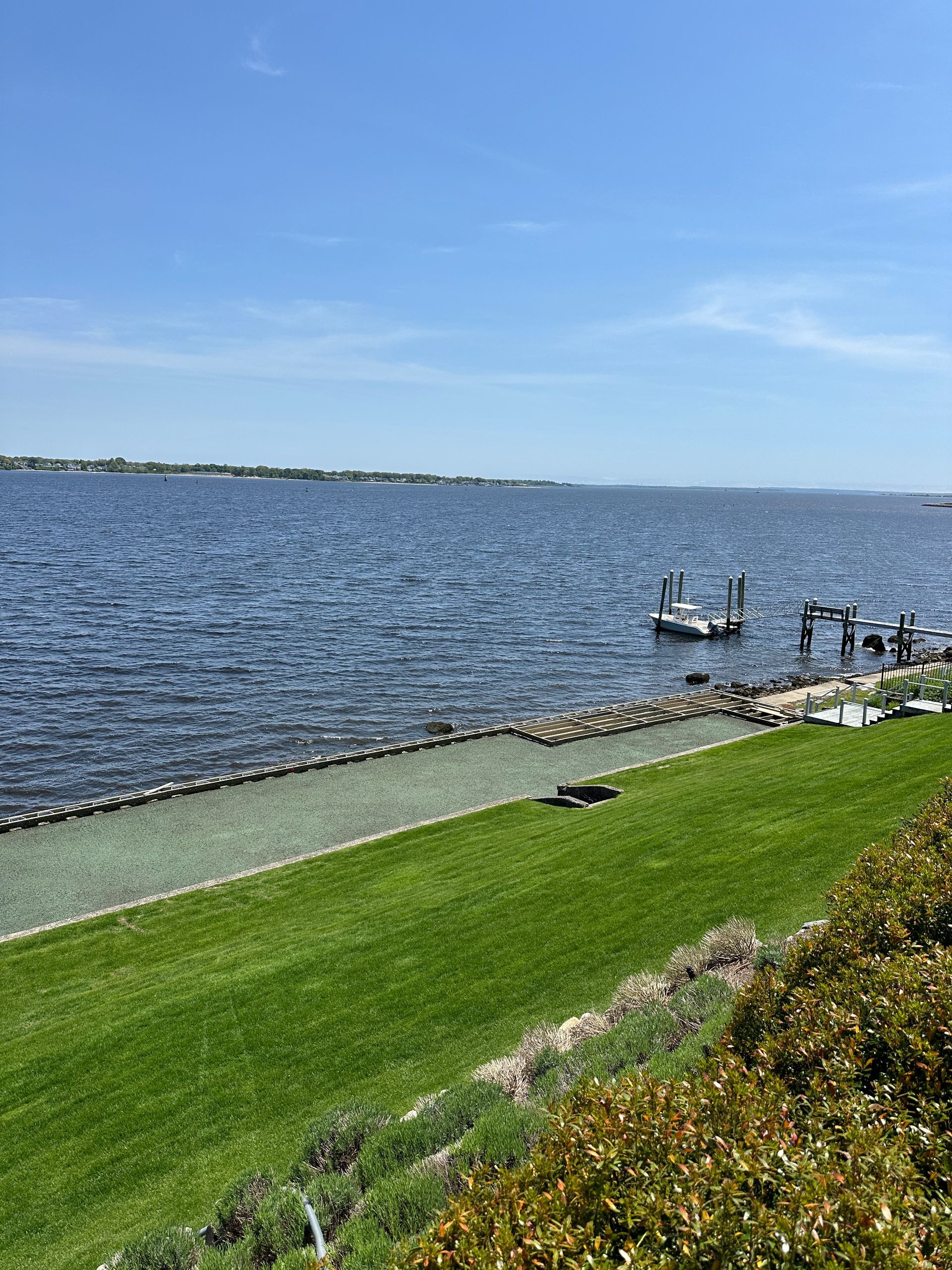 A large body of water with a grassy shoreline and a dock.