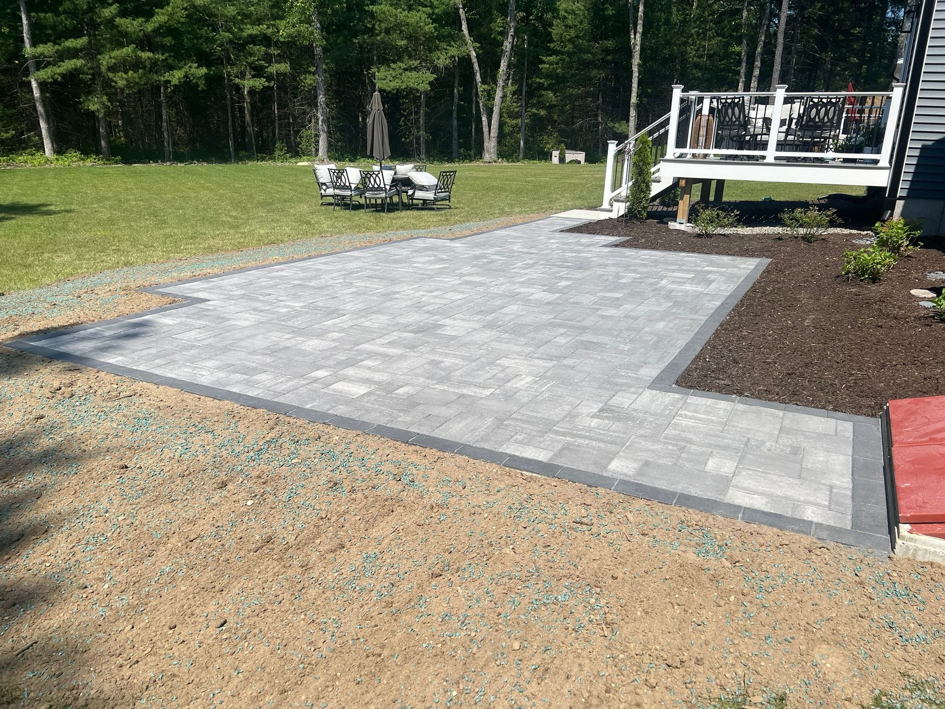 A patio with a deck in the backyard of a house.