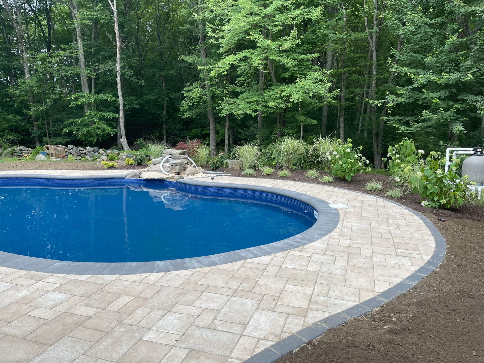 A large swimming pool surrounded by trees and a patio