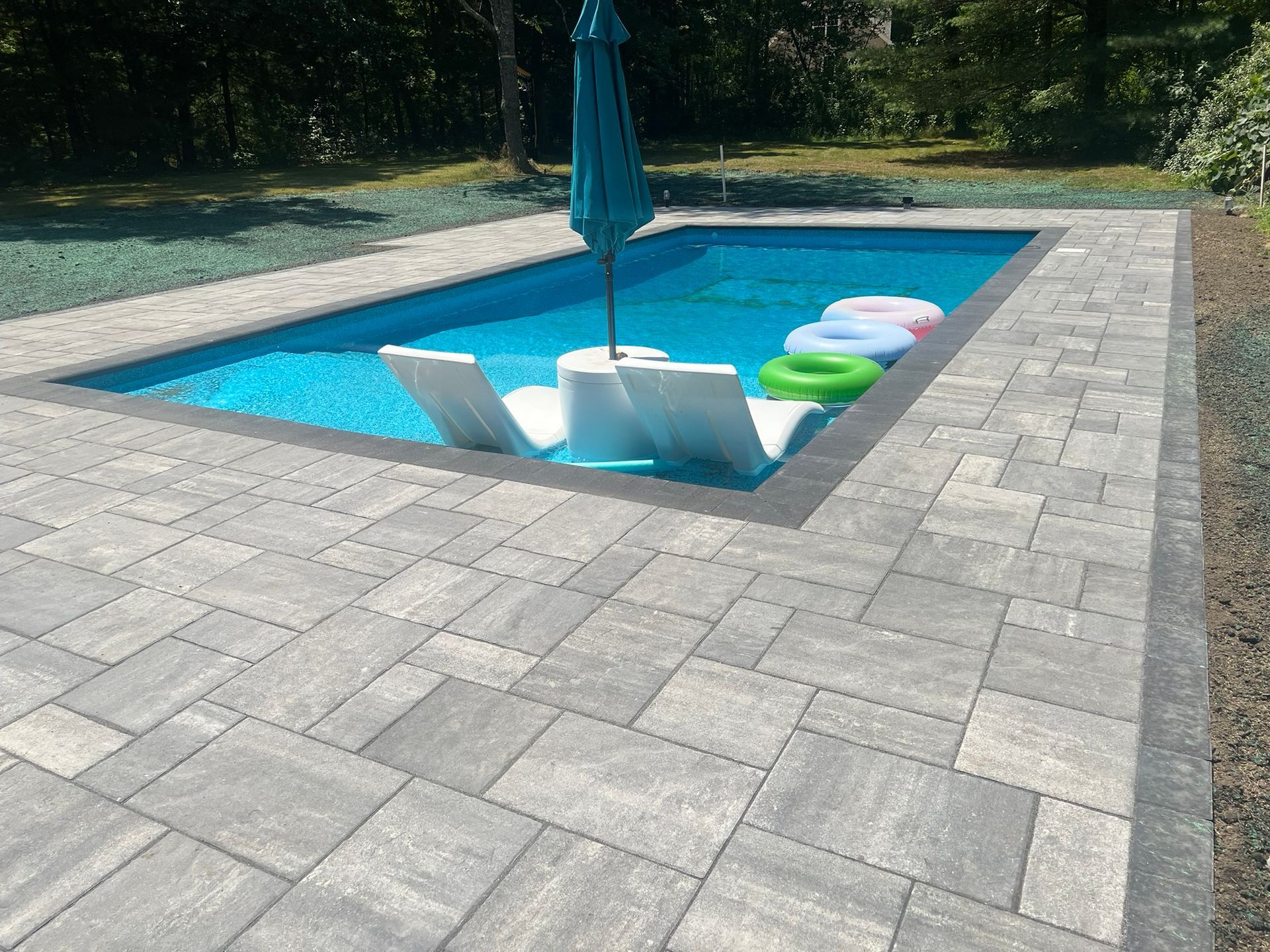 A swimming pool with chairs and a blue umbrella