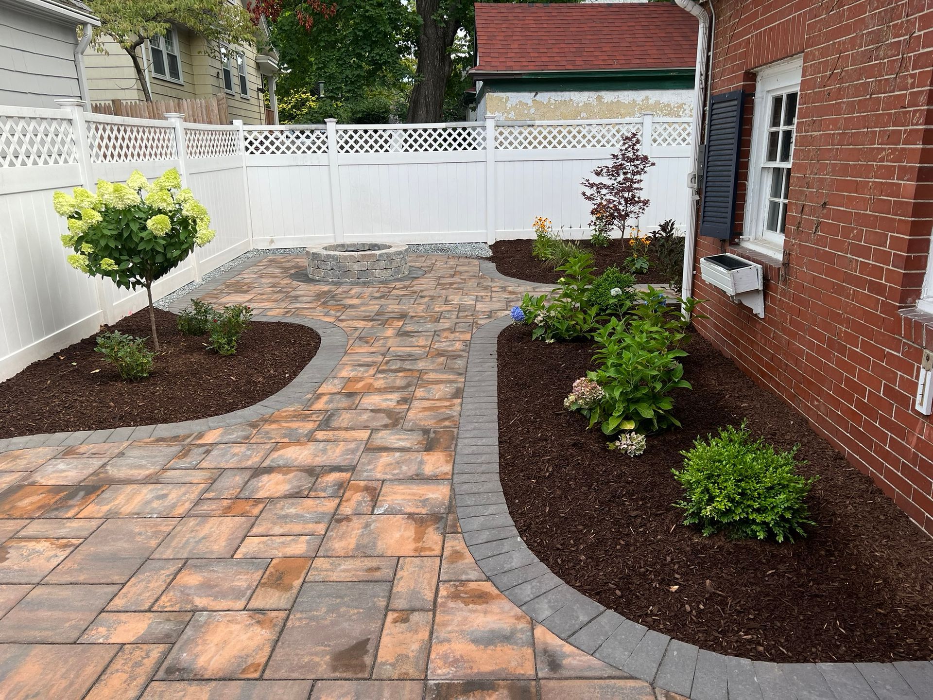 A brick house with a patio and a white fence