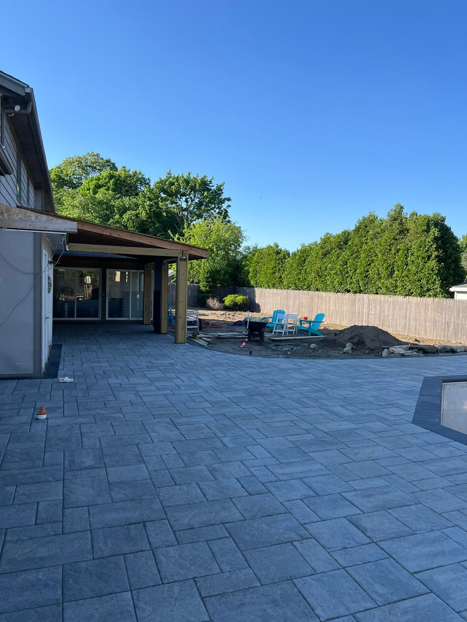 A patio with a fire pit and chairs in front of a house.