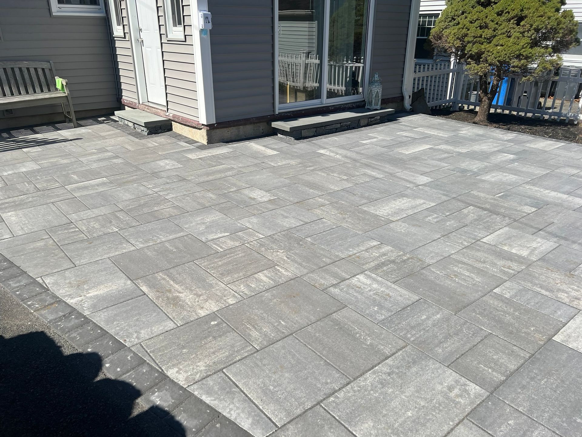 A patio with a bench in front of a house.
