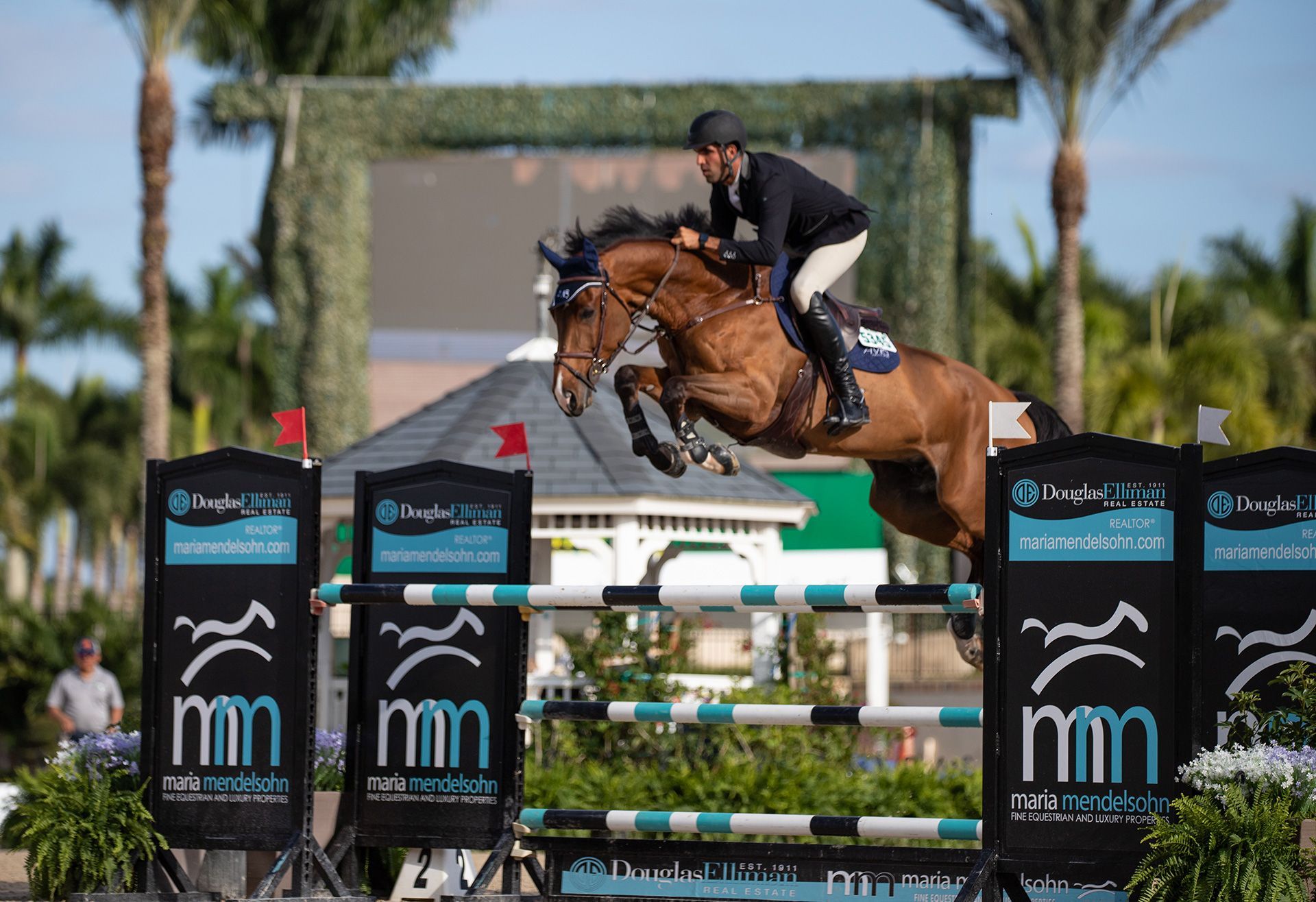 A man is riding a brown horse over a jump