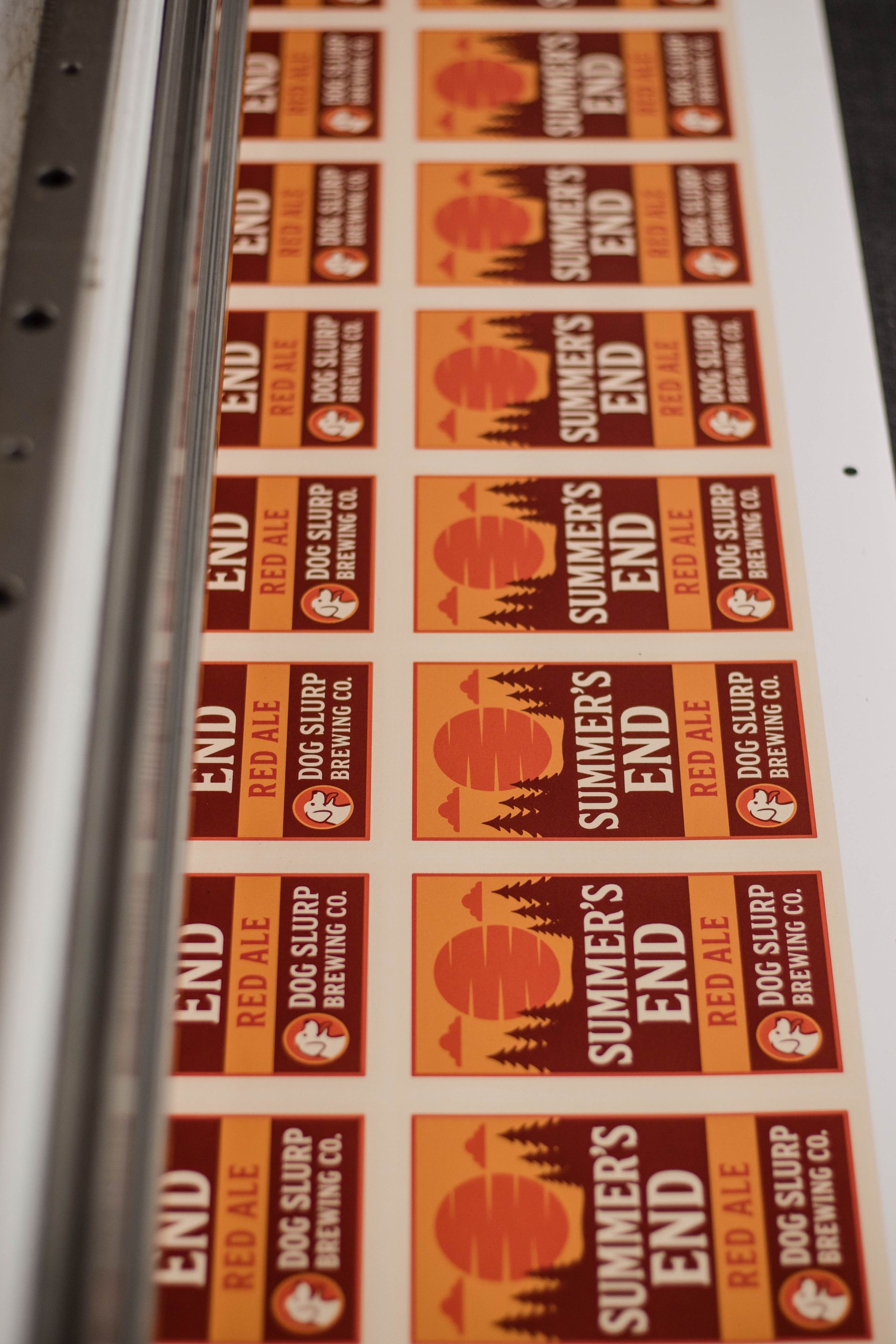 Rows of orange-and-white Summer’s End posters on a printing press or display table.