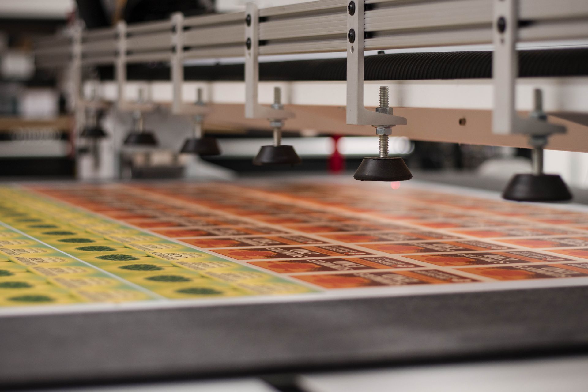 Industrial printer printing a colorful grid pattern on a sheet with suction heads above