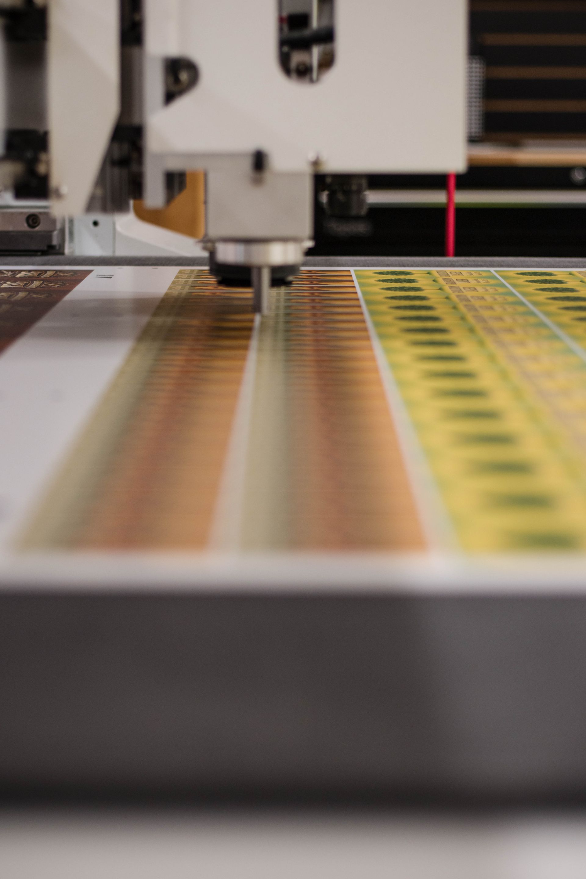Close-up of a machine printing on a colorful sheet with green and yellow stripes