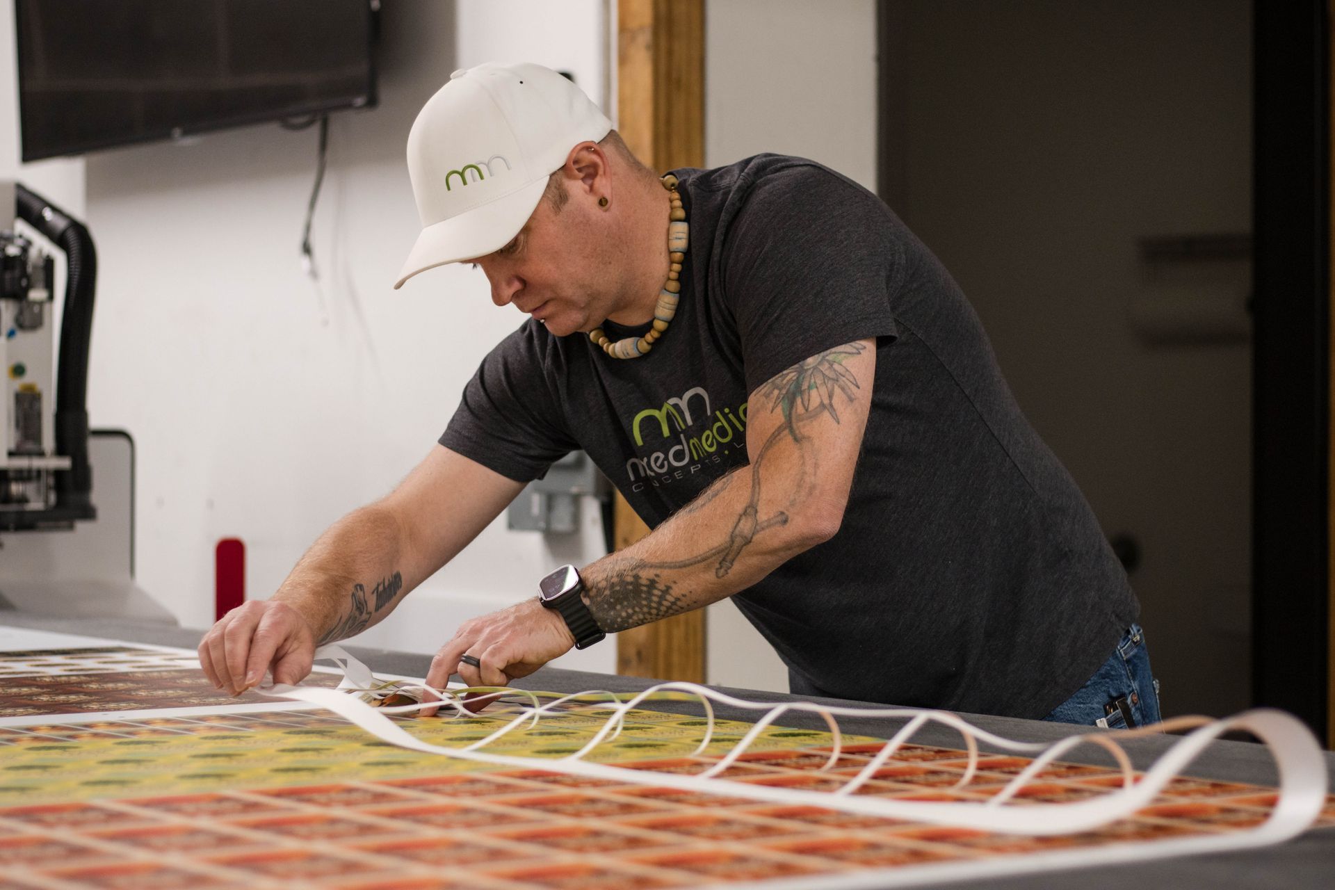 Person bending over a table, arranging colorful cable loops in a workshop.
