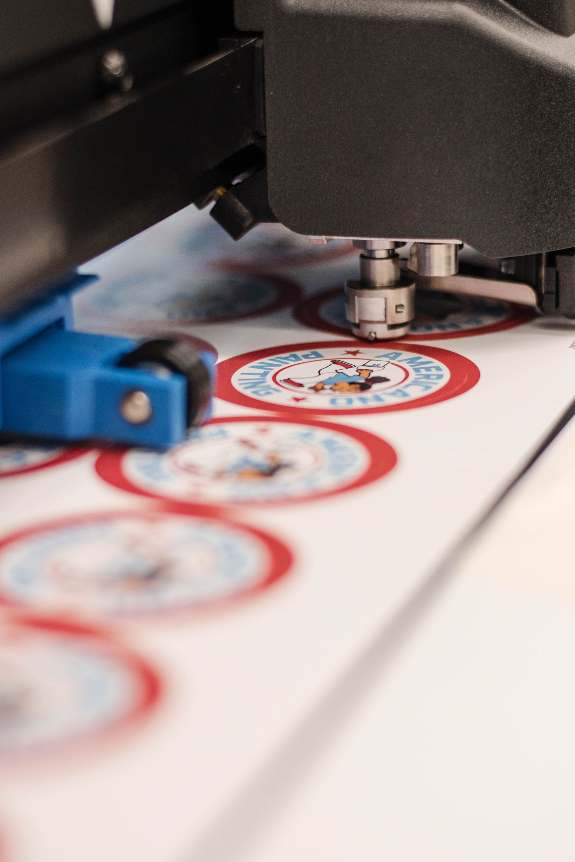 Sticker label being printed on a machine, with red and blue circular designs on white paper