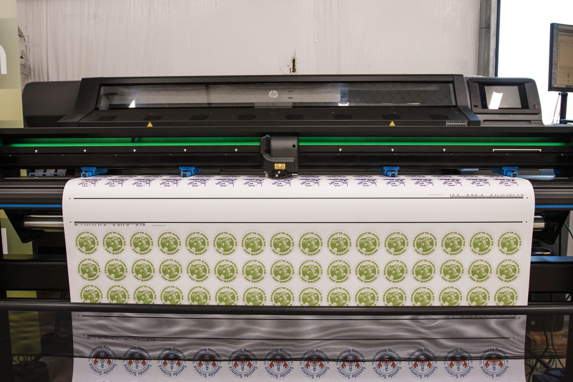 Large printer outputting a sheet with repeating green circular patterns
