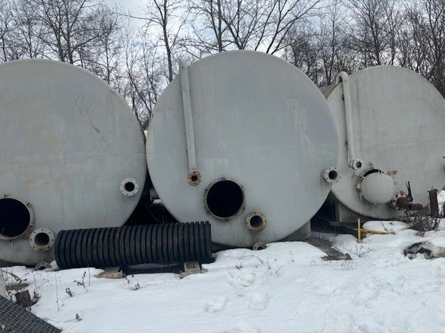Three large metal tanks are sitting in the snow.