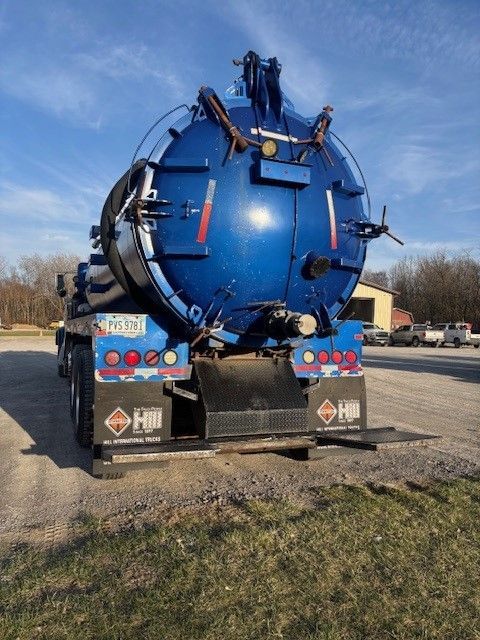 A blue vacuum truck is parked on the side of the road