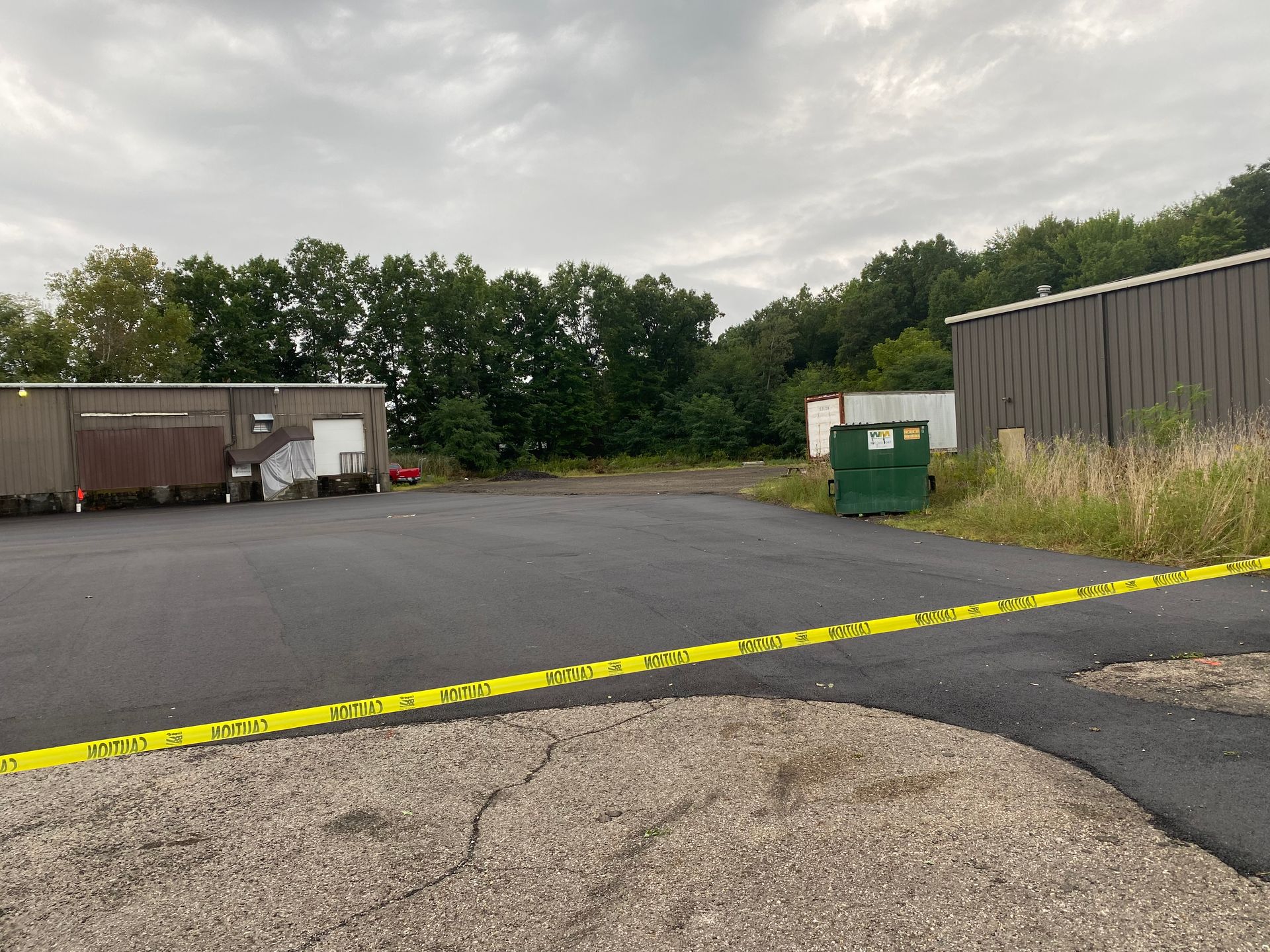 An empty parking lot with a green dumpster in the middle of it