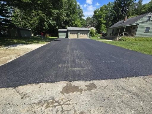 A newly paved driveway with a house in the background