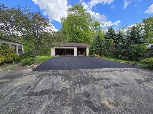 A driveway with a garage and a house in the background
