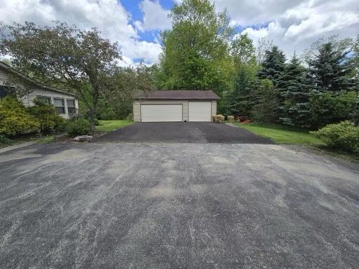 A driveway with a garage and a house in the background.