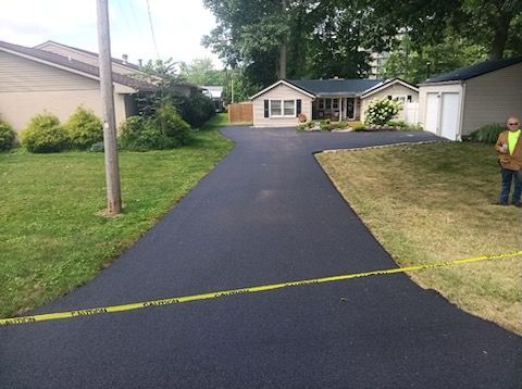 A man is standing on the side of a road next to a house.