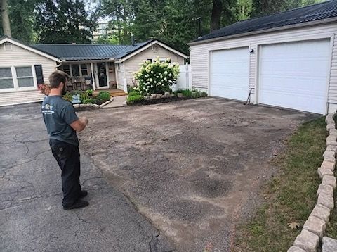 A man is standing in front of a house in a driveway.
