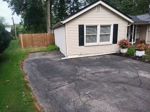 A small house with a driveway in front of it.