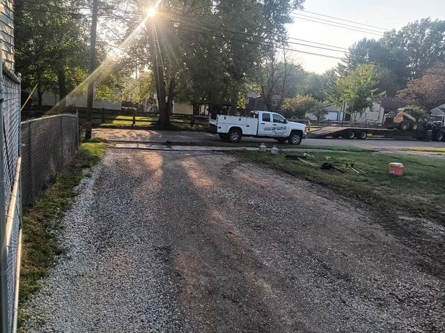 A white truck is parked on the side of a gravel road.