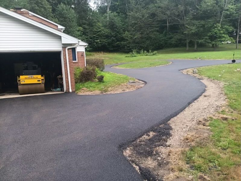 A yellow roller is parked in the driveway of a house.