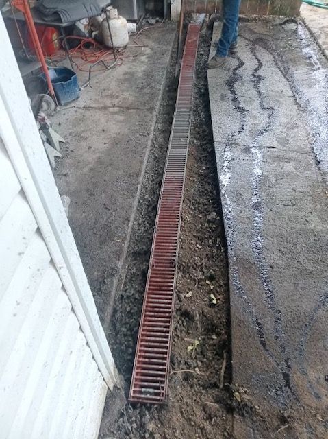 A man is standing next to a drain in the dirt.